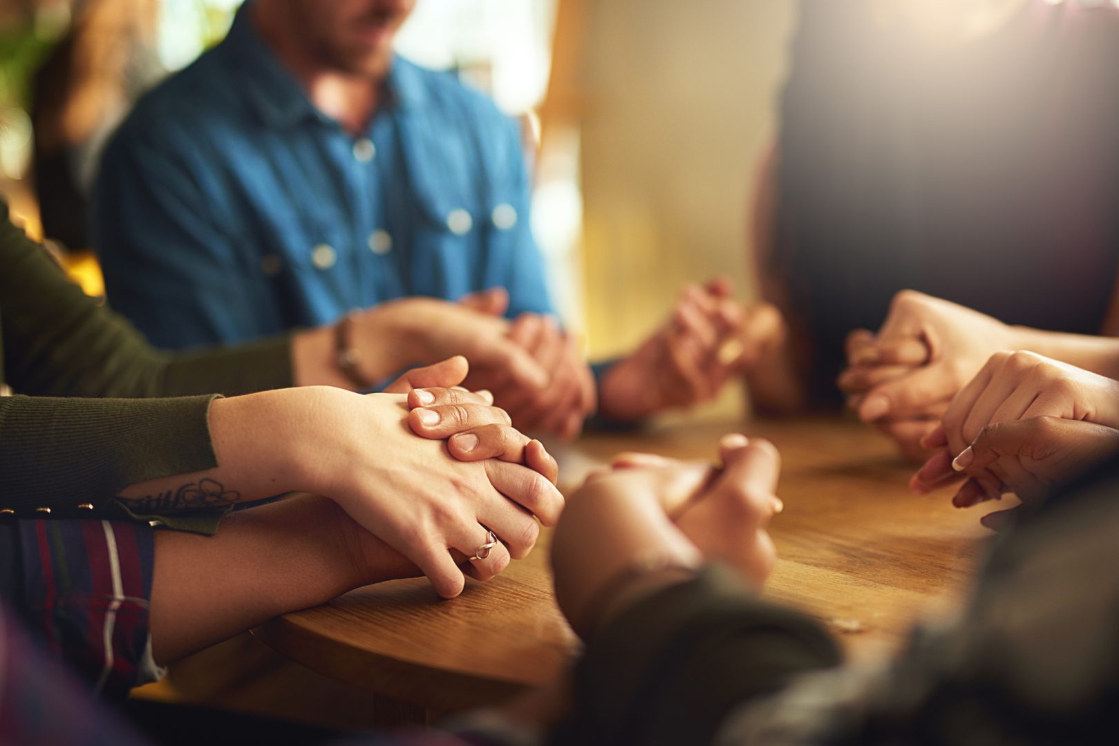 Shot of a group of people holding hands and praying together